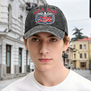 Washed black baseball cap with “USA 250” eagle print, worn by a model outdoors.
