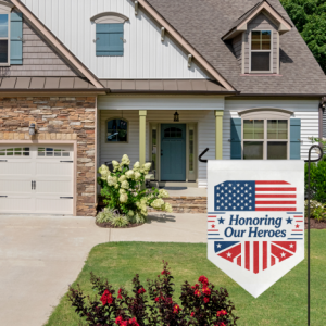 "Honoring Our Heroes" garden flag displayed in front of a suburban house with stone and white siding.