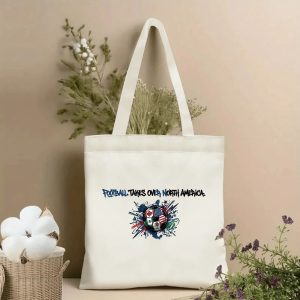Beige canvas tote bag with "Football Takes Over North America" graffiti-style text and a soccer ball print featuring Canada, USA, and Mexico flags, displayed with cotton branches and dried botanicals, 2026 World Cup fan accessory