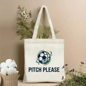 Front view of a beige canvas tote bag with a modern 2026 World Cup design. Features the "PITCH PLEASE" text above a circular logo: a stylized soccer ball encircled by blue and green curved lines, accented with tiny stars and a golden shooting star, styled with cotton stems and roses.