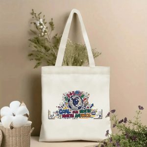 Front view of a beige canvas tote bag with a vibrant 2026 World Cup design. Features a colorful doodle-style globe emblem, "GOAL FOR NORTH AMERICA" lettering, North American country flags, soccer balls, cacti, and festive details, styled with cotton stems and dried botanicals.