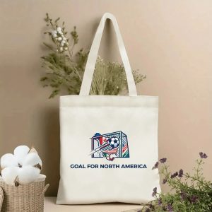 Front view of a beige canvas tote bag with a premium 2026 World Cup design. Features a dynamic soccer goal emblem integrating North American country flags, a classic soccer ball, and the bold "GOAL FOR NORTH AMERICA" text in navy blue, styled with cotton stems and dried botanicals.