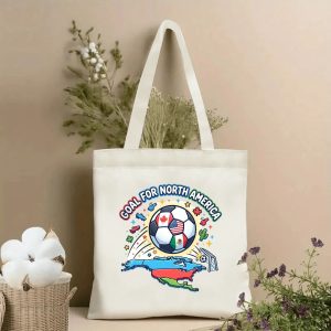 Front view of a beige canvas tote bag with a vibrant 2026 World Cup design. Features a bold "GOAL FOR NORTH AMERICA" arched text, a USA/Canada/Mexico flag soccer ball, North America map, goal net, and festive soccer-themed icons, styled with cotton stems and dried botanicals.
