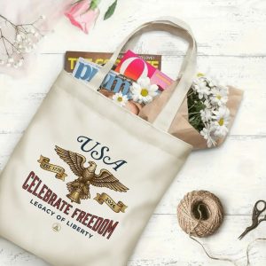 Canvas tote bag with the same America 250th print, shown open with books and flowers inside, on a white wooden surface.