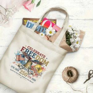 Canvas tote bag with the same America 250th print, shown open with books and flowers inside, on a white wooden surface.