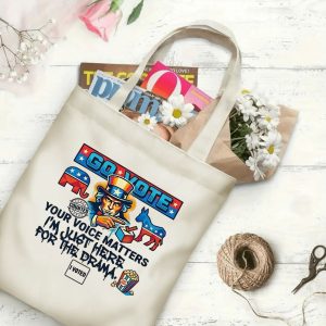 Natural canvas tote bag with a "Go Vote" graphic print, shown open with magazines and flowers inside, placed on a white wooden background.