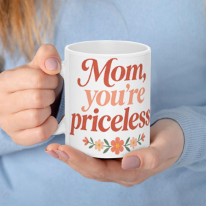 A white 11oz ceramic coffee mug held in hands, featuring "Mom, you're priceless" in coral gradient cursive text with a small floral border at the bottom.