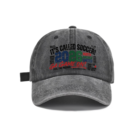 Dark gray vintage washed cotton adjustable dad hat, front bold multi‑color graffiti‑text soccer print with “It’s Called Soccer! 2026 Go Game On” slogan, retro faded finish, casual sports baseball cap flat lay