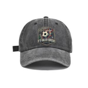 Dark grey vintage washed adjustable dad hat with retro shield‑badge flaming soccer‑ball graphic, bold “It’s Called Soccer!” slogan and North America 2026 World Cup details, casual fan baseball cap