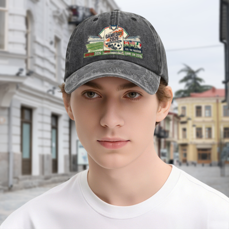 Young man wearing dark grey vintage washed “Gameday 2026 United” soccer‑graphic dad hat, outdoor street‑style portrait of 2026 World Cup soccer fan with casual retro headwear
