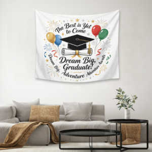 Graduation tapestry wall decor with "The Best is Yet to Come" and "Dream Big, Graduate!" text, featuring graduation cap, diploma, balloons, and fireworks print, hung in a living room as a festive backdrop.