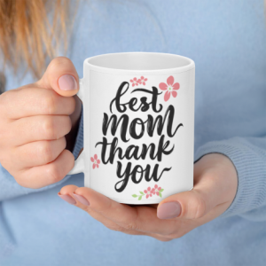 A white 11oz ceramic coffee mug held in hands, featuring elegant black cursive text reading "best mom thank you" surrounded by delicate pink flowers.