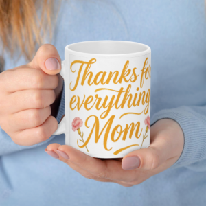 A white 11oz ceramic coffee mug held in hands, featuring "Thanks for everything, Mom" in elegant gold cursive text with pink carnation accents.