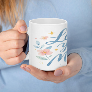 A white 11oz ceramic coffee mug held in hands, featuring "Love you, Mom!" in soft blue watercolor cursive text with delicate pink flowers and sparkles.