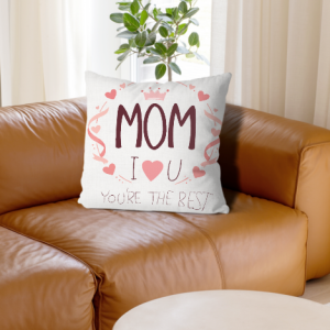 White linen throw pillow cover with "MOM I ❤️ U You're The Best" print, maroon lettering with pink crown, hearts and ribbon accents, home decor for Mother’s Day