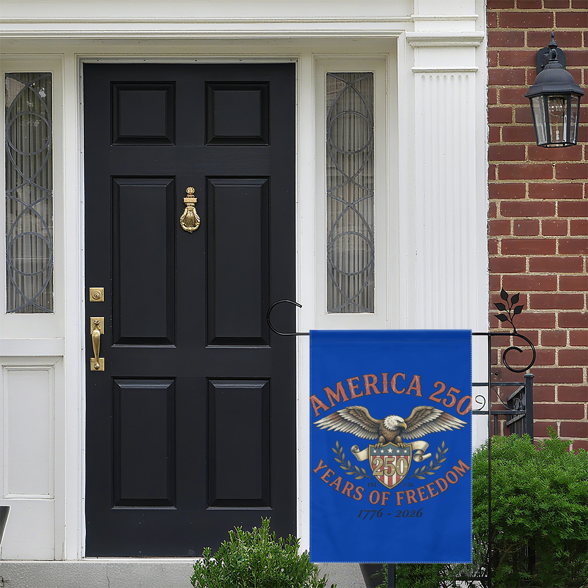 "America 250" garden flag displayed on a porch near a black front door, adding patriotic decor to a home’s entrance.