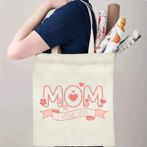 A person carrying the "MOM" print canvas tote bag over their shoulder, showing its comfortable straps and roomy design with rolled papers inside.