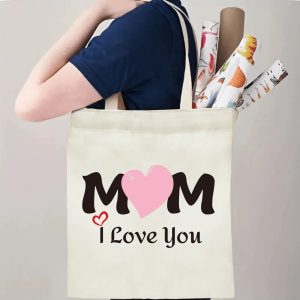 A person carrying the "MOM I Love You" print canvas tote bag over their shoulder, showing its comfortable straps and roomy design with rolled papers inside.