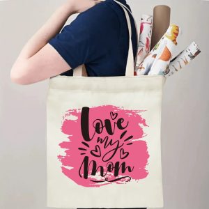 A person carrying the "love my mom" print canvas tote bag over their shoulder, showing its comfortable straps and roomy design with rolled papers inside.