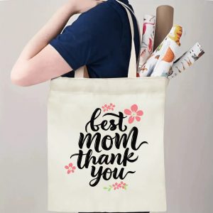 A person carrying the "best mom thank you" print canvas tote bag over their shoulder, showing its comfortable straps and roomy design with rolled papers inside.