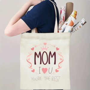 A person carrying the "MOM I ❤️ U You're the Best" print canvas tote bag over their shoulder, showing its comfortable straps and roomy design with rolled papers inside.