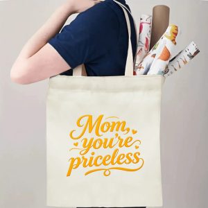 A person carrying the "Mom, you're priceless" print canvas tote bag over their shoulder, showing its comfortable straps and roomy design with rolled papers inside.