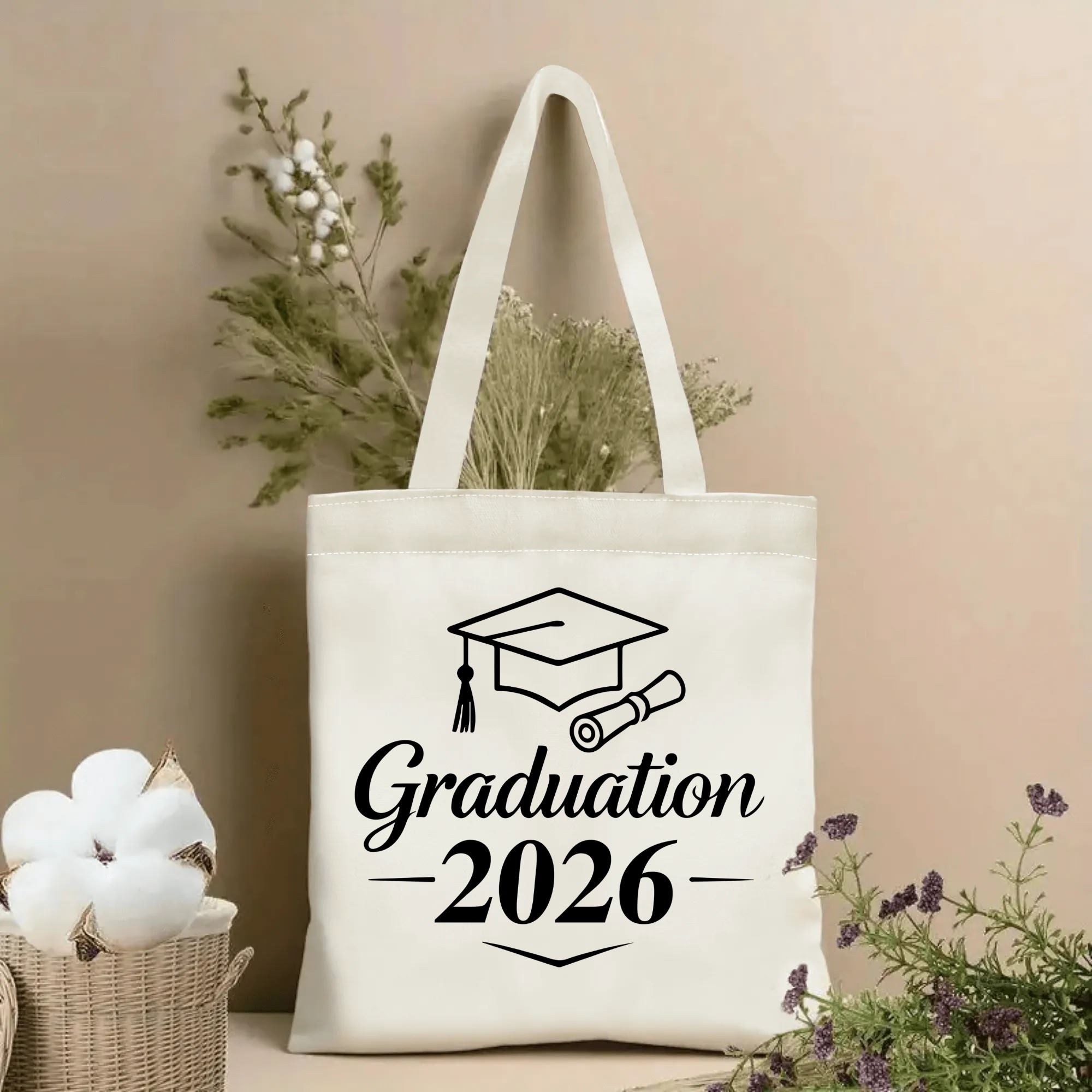 2026 Graduation canvas tote bag with graduation cap and diploma print, beige reusable tote bag for graduation gift, styled with dried flowers