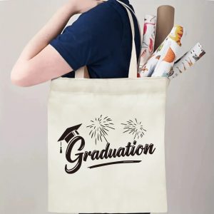 Person carrying natural canvas graduation tote bag with graduation cap, fireworks and "Graduation" cursive print, casual graduation‑day reusable gift bag
