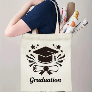 Person carrying natural canvas graduation tote bag with graduation cap, diploma and star wreath print, casual milestone‑celebrating reusable gift bag