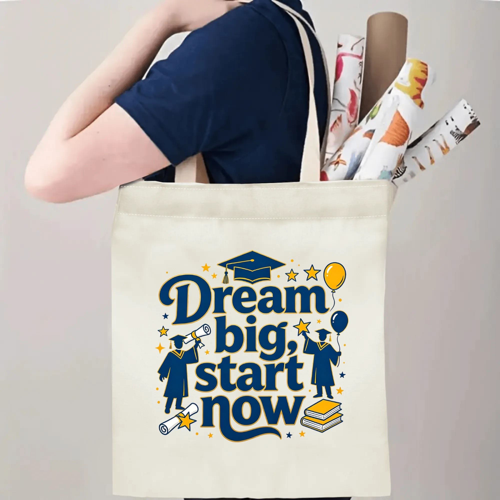 Person carrying natural canvas graduation tote bag with "Dream big, start now" motivational quote, graduate silhouettes, cap and balloon print, casual milestone‑celebrating reusable gift bag