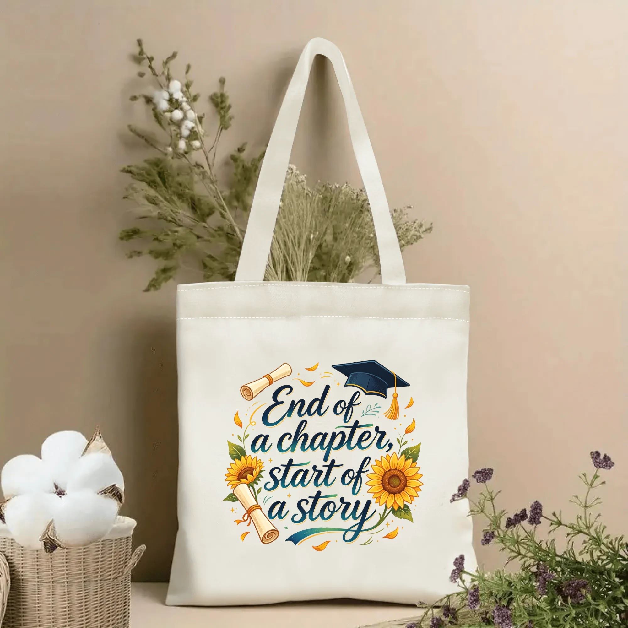 Natural canvas graduation‑themed tote bag featuring the quote "End of a chapter, start of a story" in elegant cursive lettering, decorated with graduation cap, diploma and bright sunflower wreath, styled with dried flowers for graduation gift display
