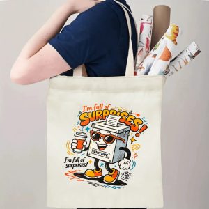 Person carrying natural canvas 2026 mid‑term election gag gift tote bag with bold colorful cartoon ballot box print and humorous "I'm full of surprises!" slogan, reusable political accessory for rallies and everyday errands
