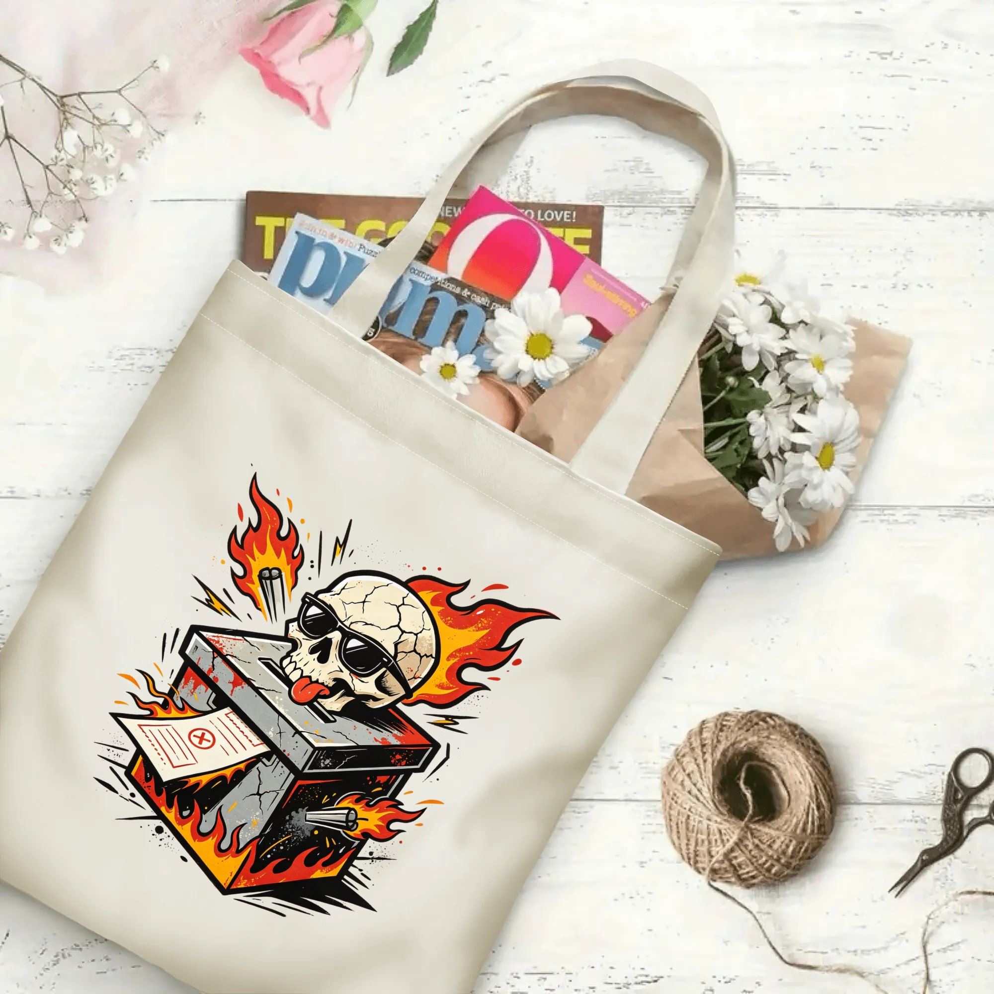 Flat‑lay shot of natural canvas political novelty tote bag with bold hot‑rod tattoo‑art skull ballot box print, blazing fire details and rebellious voting theme, decorated with daisies, ideal casual daily‑wear bag for voters