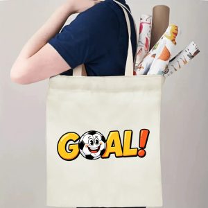 Person carrying natural canvas soccer fan‑gift tote bag with vibrant cartoon "GOAL!" design and cheerful soccer‑ball mascot, reusable sports accessory for match days, training or everyday errands