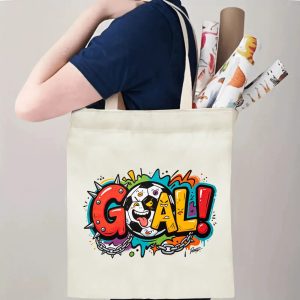 Person carrying natural canvas edgy soccer fan‑gift tote bag with vibrant graffiti‑punk "GOAL!" design, spiked and chain accents, reusable sports accessory for match days, fan events or everyday errands