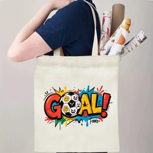 Person carrying natural canvas trendy soccer fan‑gift tote bag with bright graffiti‑pop "GOAL!" design and playful emoji soccer ball, reusable sports accessory for match days, fan events or everyday errands