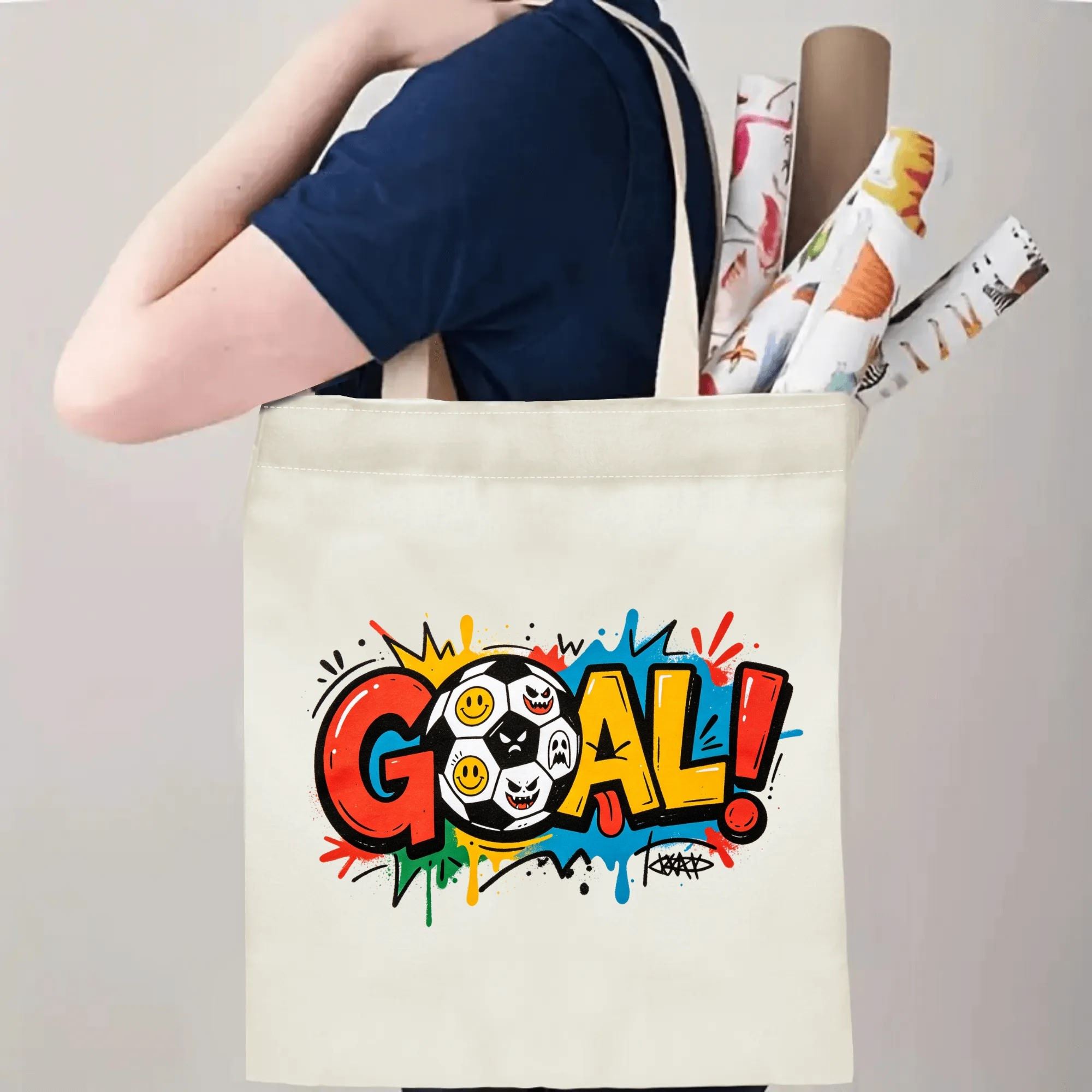 Person carrying natural canvas trendy soccer fan‑gift tote bag with bright graffiti‑pop "GOAL!" design and playful emoji soccer ball, reusable sports accessory for match days, fan events or everyday errands