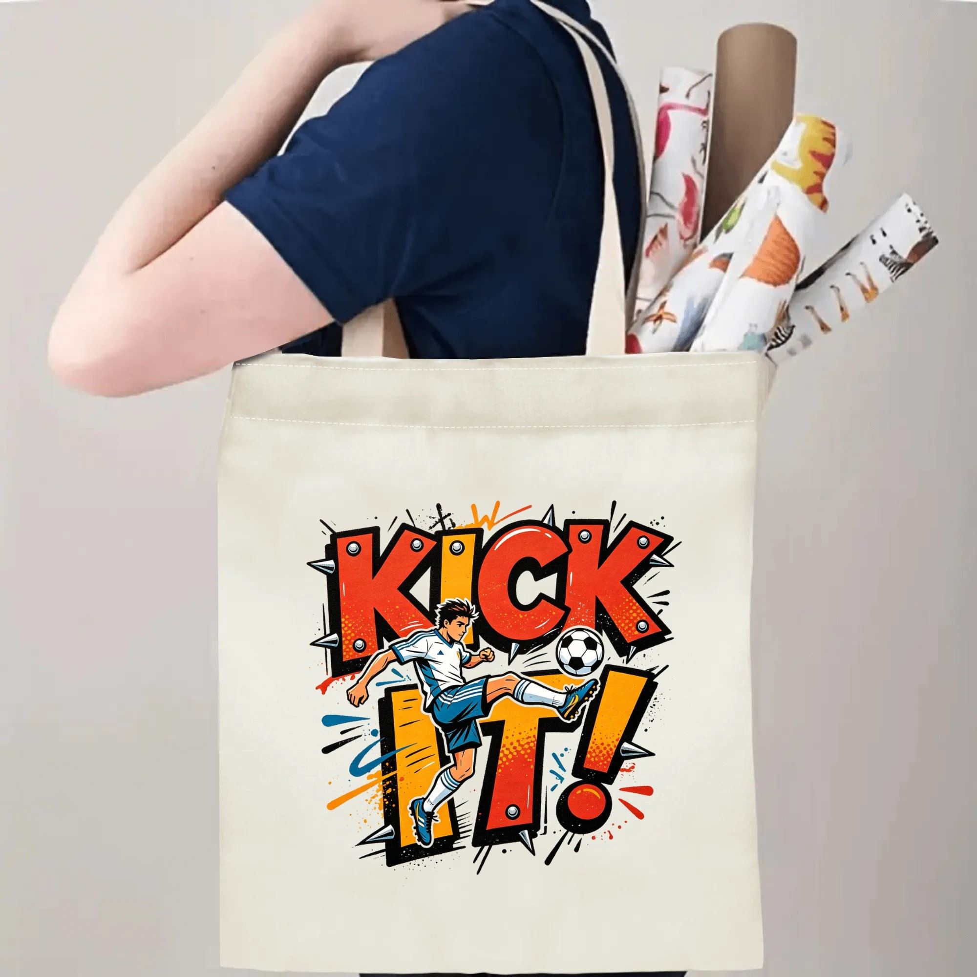 Person carrying natural canvas trendy soccer fan‑gift tote bag with vibrant spiked‑graffiti "KICK IT!" design and action soccer‑player mascot, reusable sports accessory for match days, fan events or everyday errands