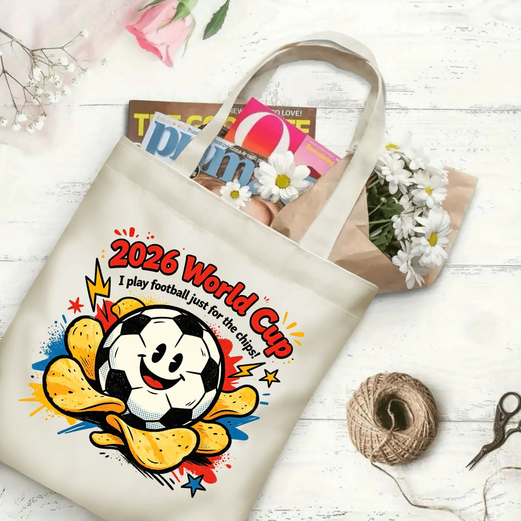 Flat‑lay shot of natural canvas novelty football tote bag with lighthearted snack‑themed soccer graphic, cute chip‑surrounded soccer‑ball character and witty tournament‑humor text, decorated with daisies, ideal casual daily‑wear bag for World Cup fans