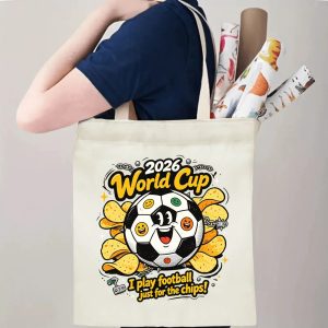 Person carrying natural canvas 2026 World Cup fan‑gift tote bag with vibrant rebellious punk‑style emoji soccer‑chips mascot design, reusable sports accessory for tournament viewing, fan events or everyday errands