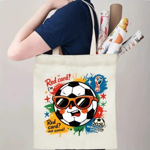 Person carrying natural canvas 2026 World Cup fan‑gift tote bag with lively street‑cartoon cool soccer‑ball mascot design, reusable sports accessory for tournament viewing, fan events or everyday errands