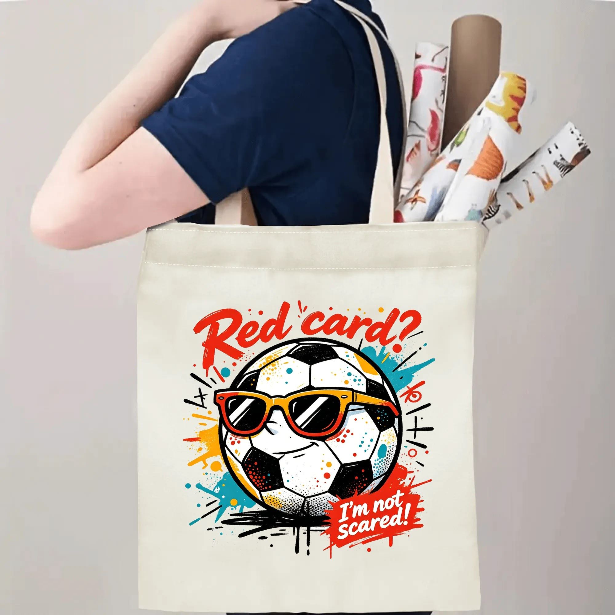 Person carrying natural canvas soccer fan‑gift tote bag with cool laid‑back street‑cartoon soccer‑ball mascot design, reusable sports accessory for match days, fan events or everyday errands