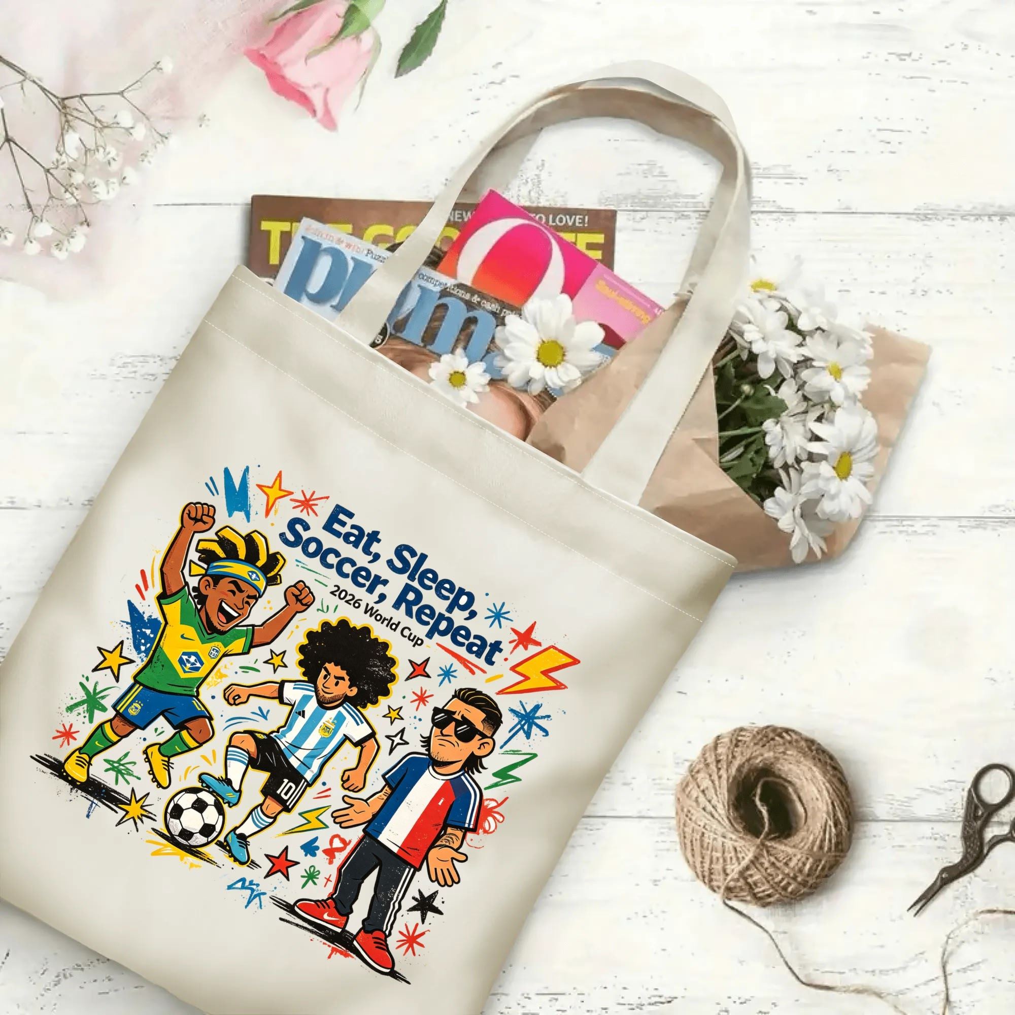Flat‑lay shot of natural canvas novelty football tote bag with lively international soccer star cartoon graphic, fun soccer lifestyle quote, bright colorful splash‑style details, decorated with daisies, ideal casual daily‑wear bag for World Cup fans