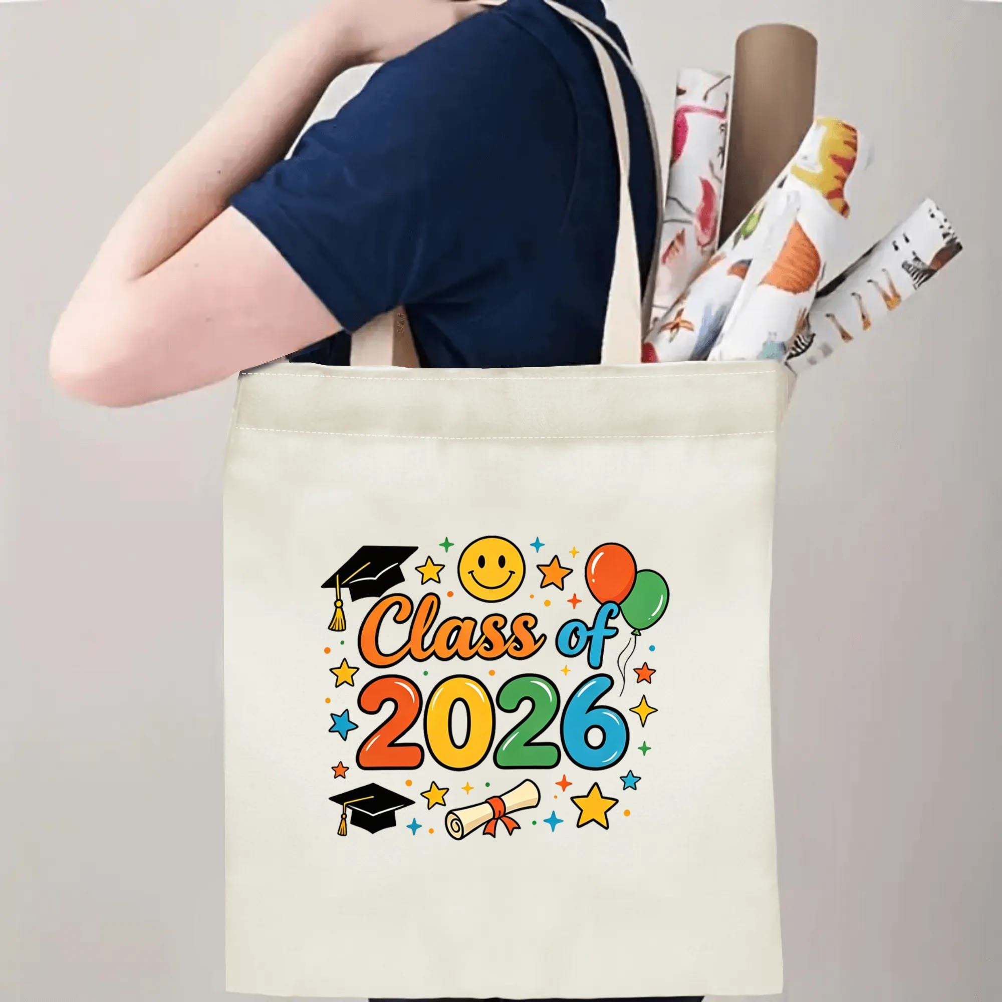 Person carrying a "Class of 2026" canvas tote bag over the shoulder, holding rolled posters and items