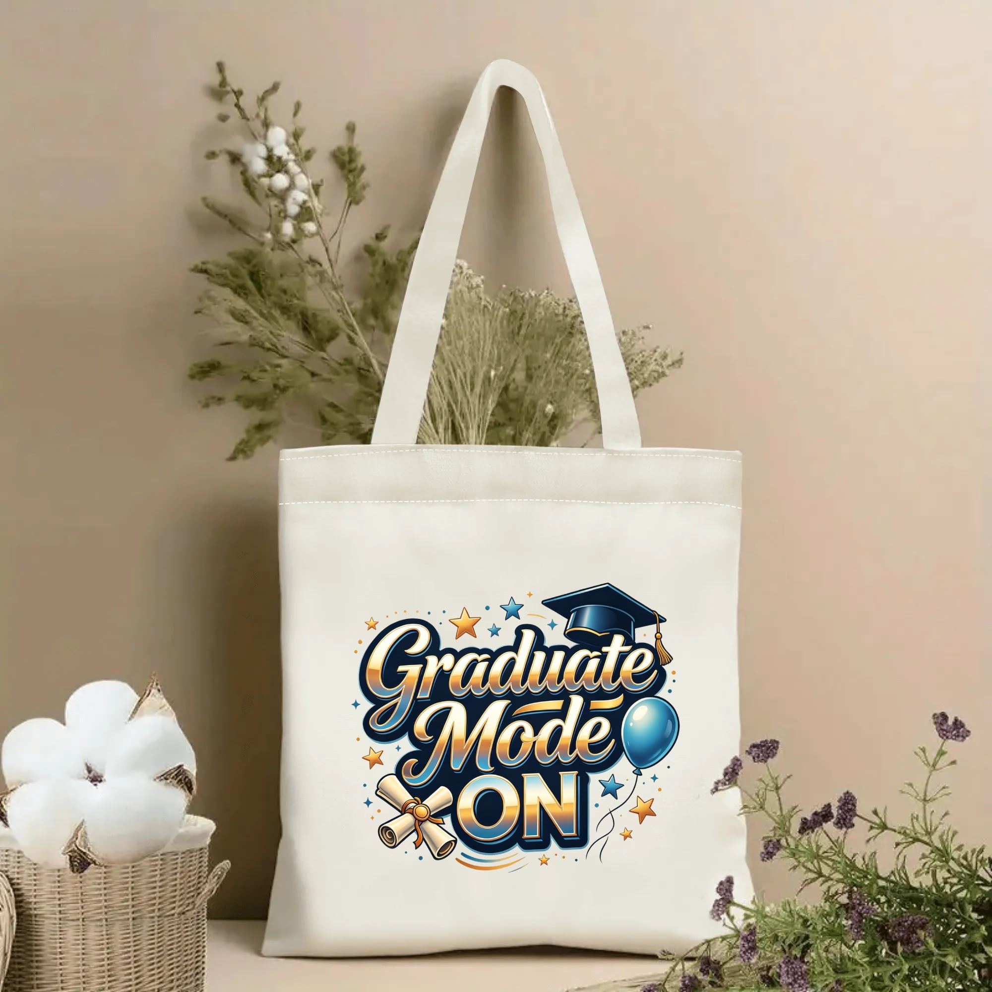 Natural canvas tote bag with "Graduate Mode ON" print, featuring graduation cap, diploma, balloon, and star accents, graduation-themed design