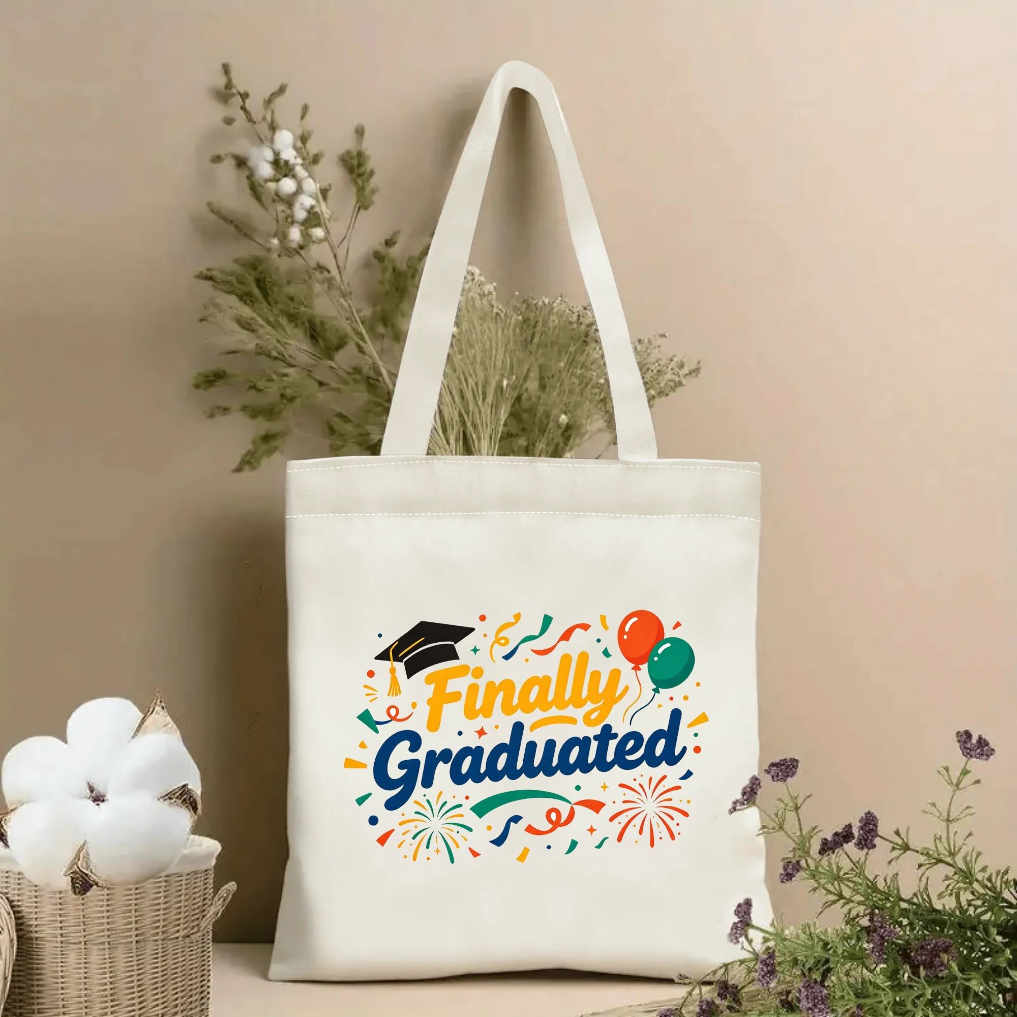 Natural canvas tote bag with “Finally Graduated” print, featuring graduation cap, balloons, confetti, and fireworks.