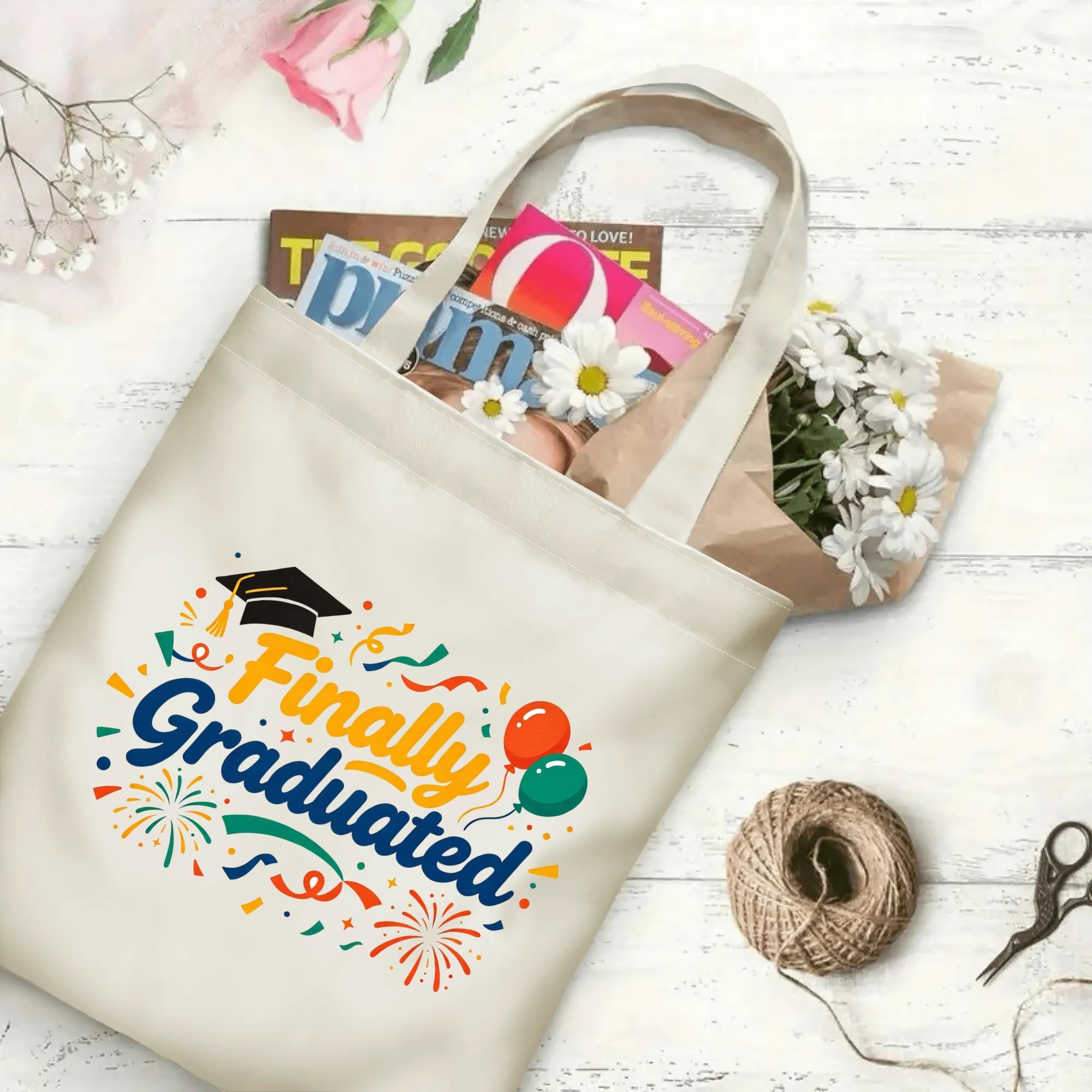 “Finally Graduated” canvas tote bag in use, holding books, flowers, and gifts.