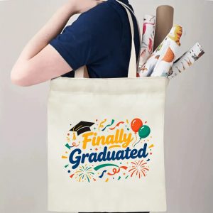 Person carrying a “Finally Graduated” canvas tote bag over the shoulder, with rolled posters and graduation essentials.