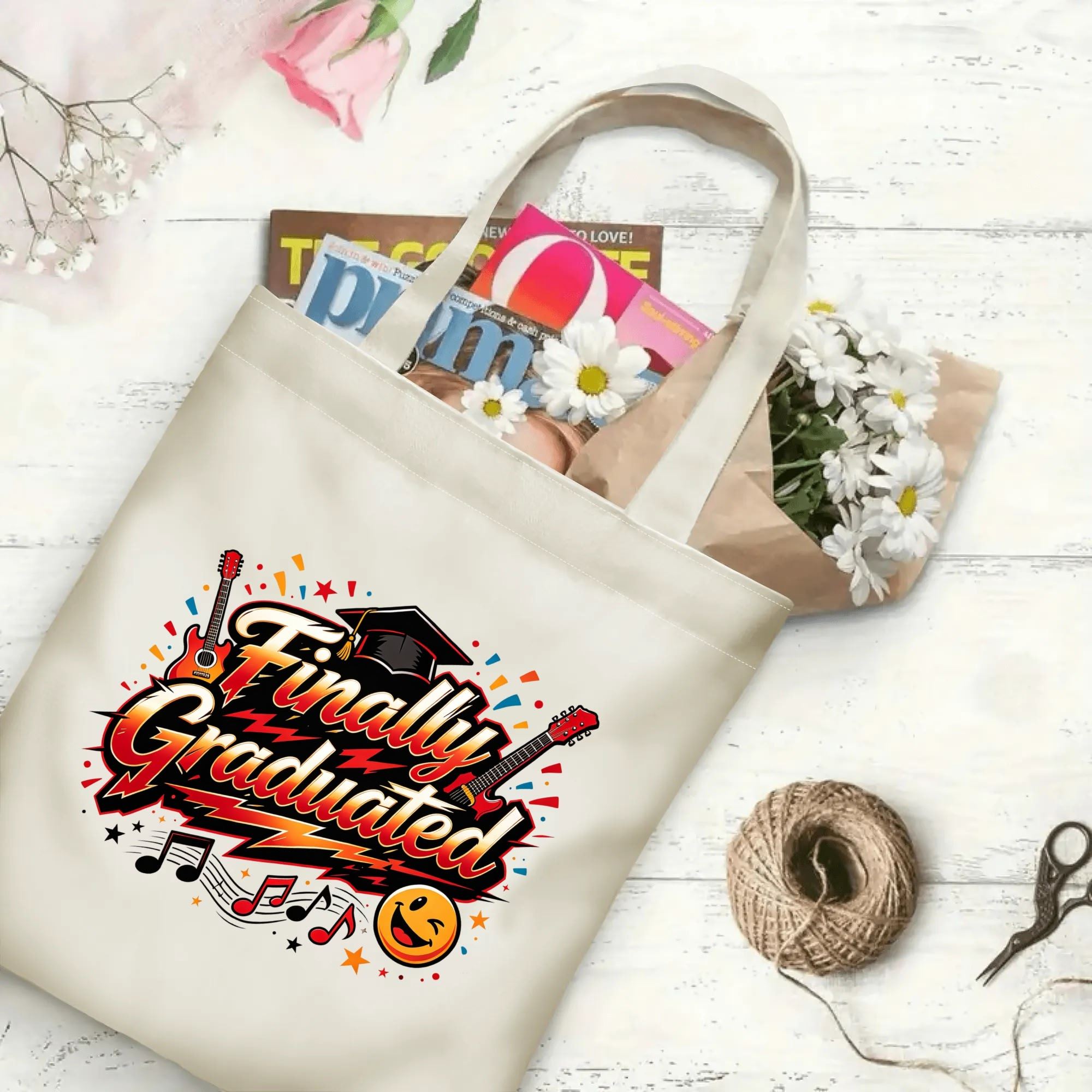 “Finally Graduated” rock‑style canvas tote bag in use, holding books, flowers, and gifts.
