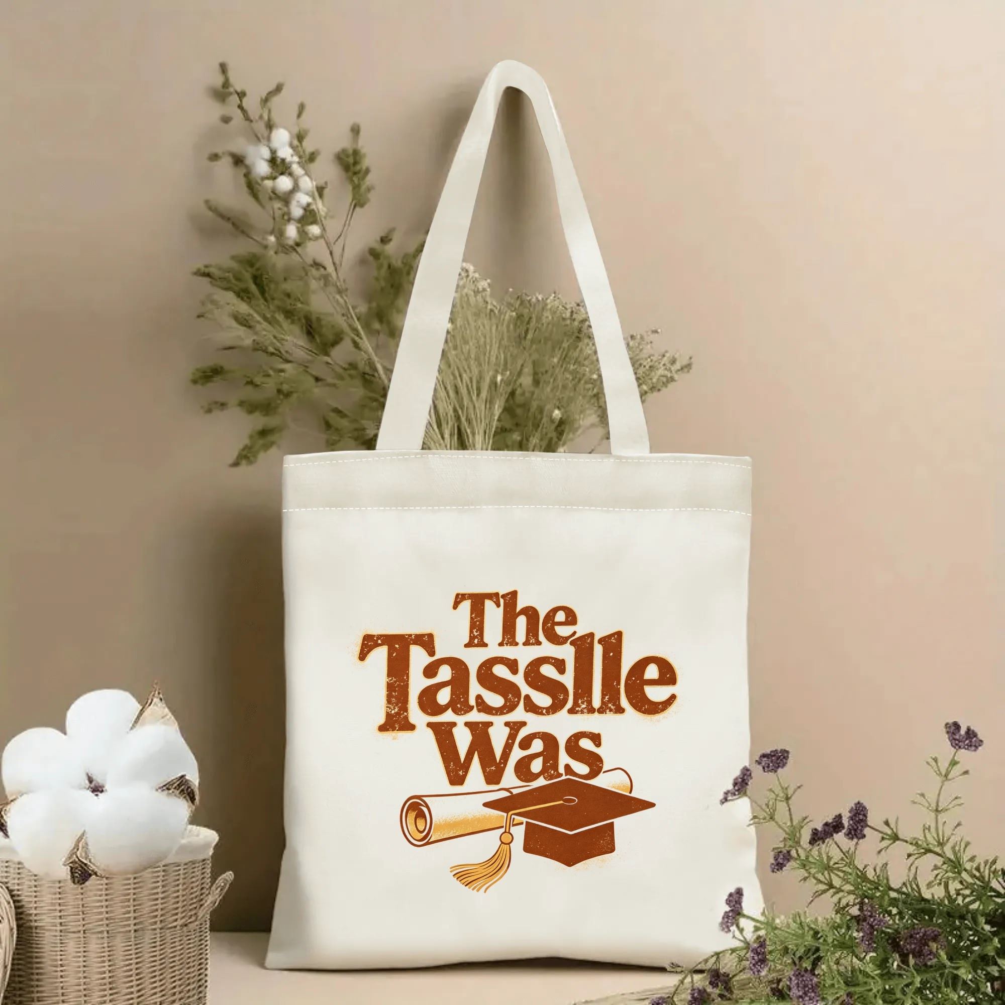 Natural canvas tote bag with “The Tassle Was” print, featuring vintage-style graduation cap, diploma, and distressed text.